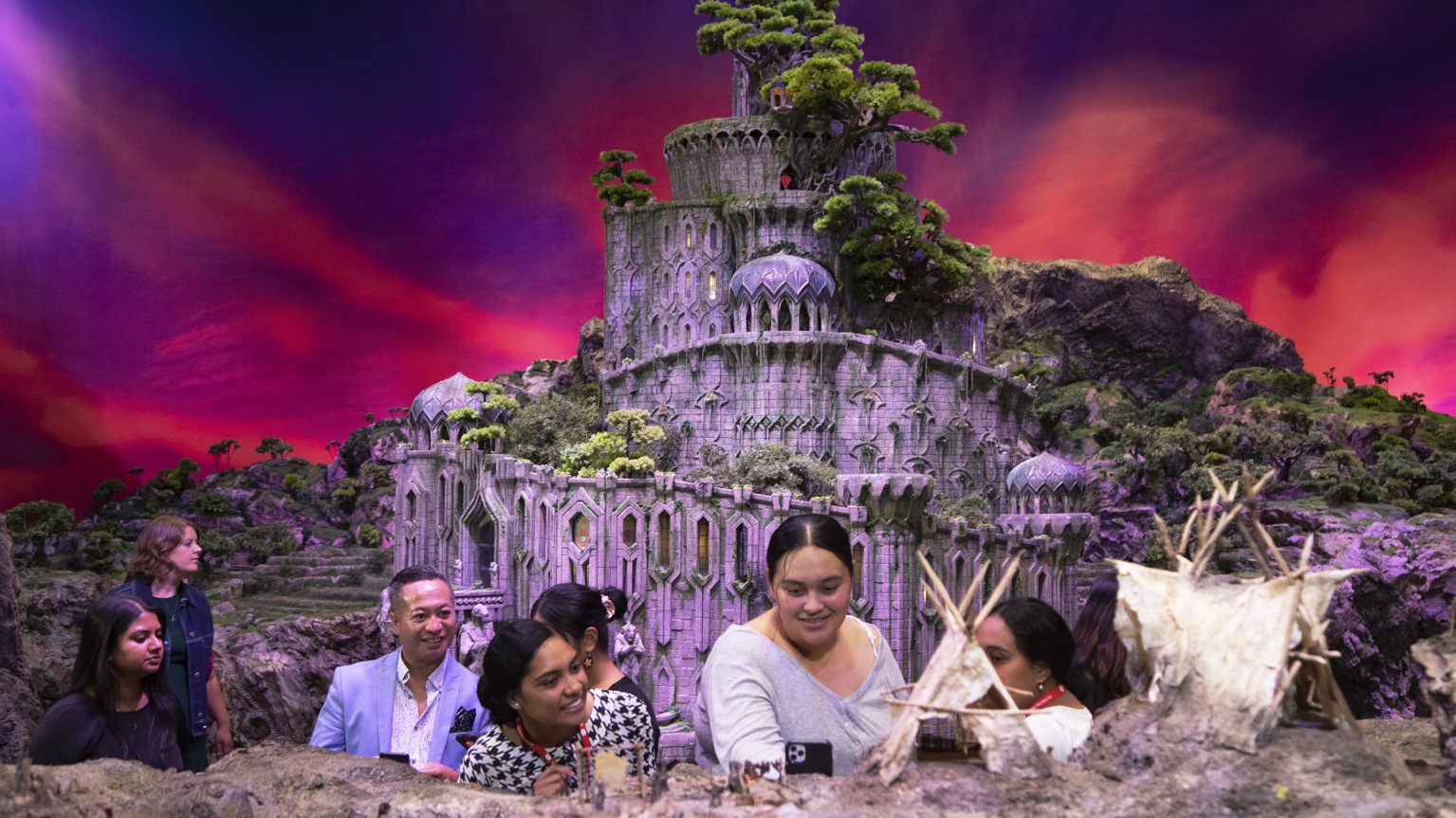 Tourists interact with model of castle and village buildings from Lord of the Rings