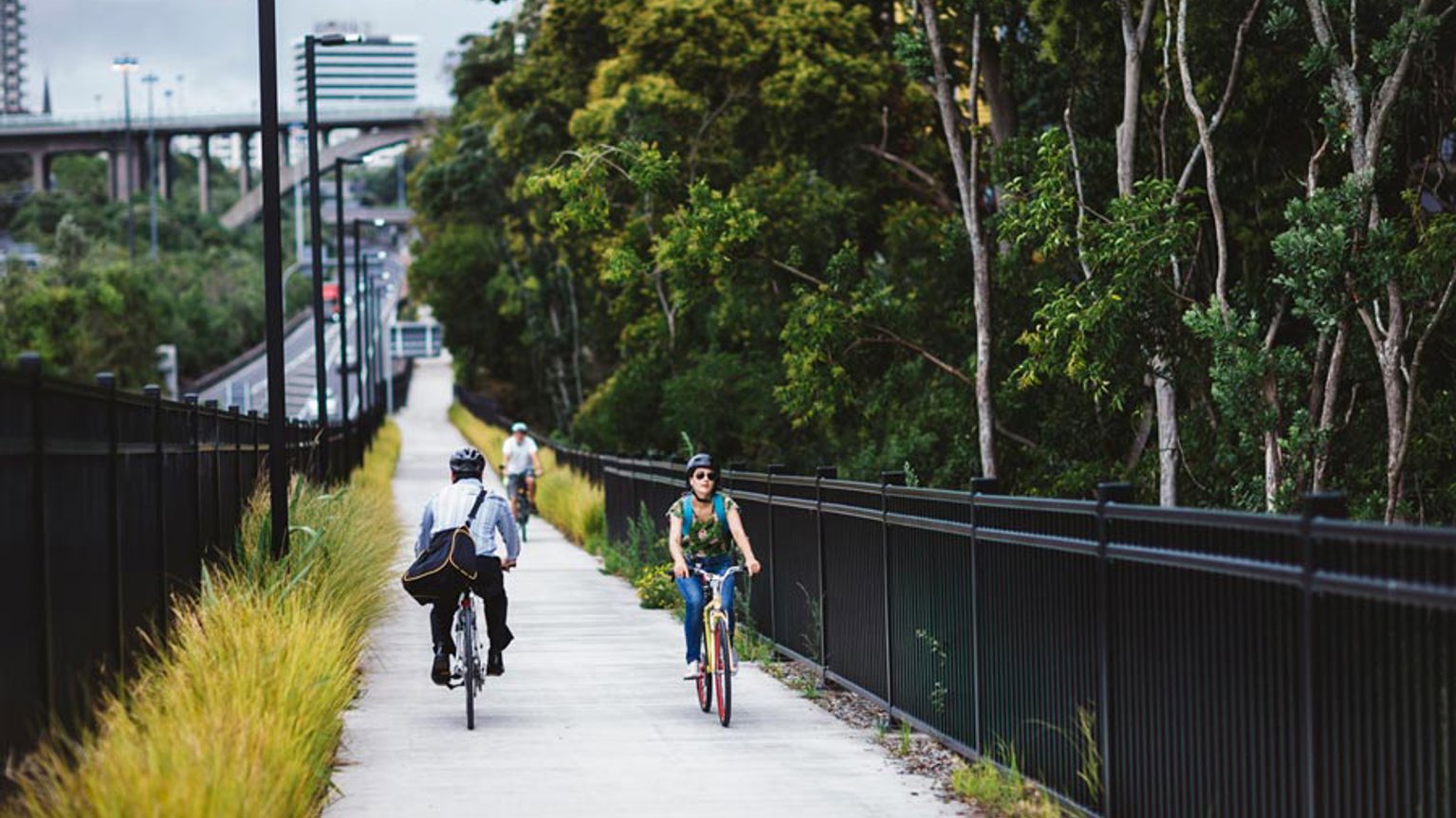 Commuters cycle along a flat, concrete path through Grafton Gully.