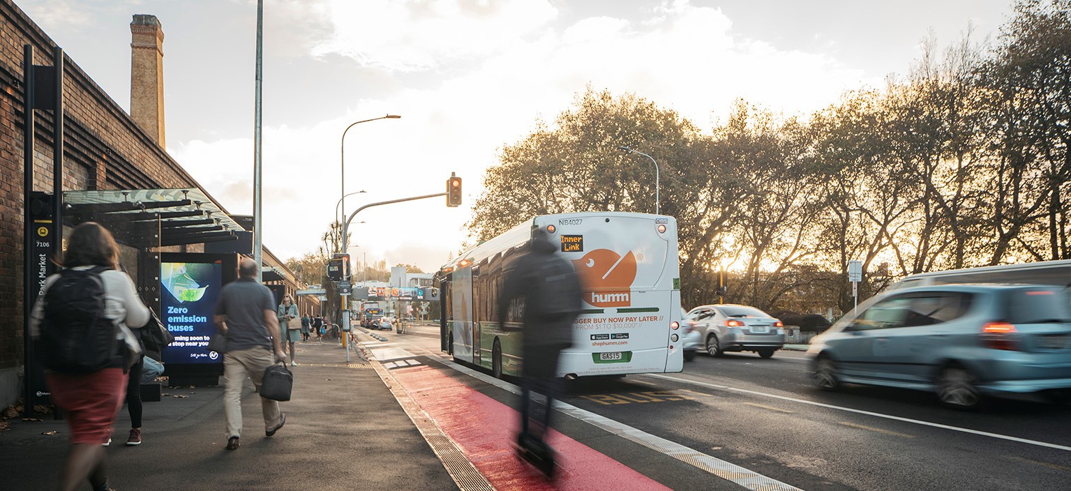 Street view with parked cars and a distant city skyline featuring the Skytower.