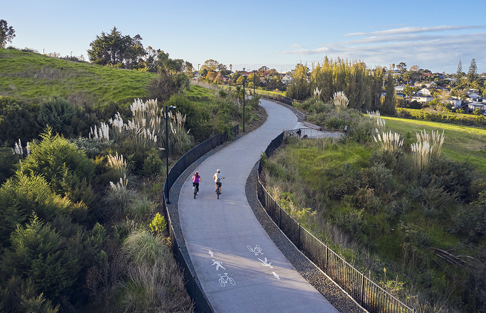 Cyclists on a cycleway through green bushes