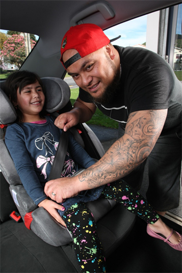 Child being strapped in a booster seat