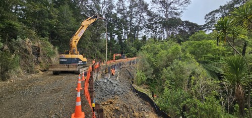 Excavator driving piles on metal road