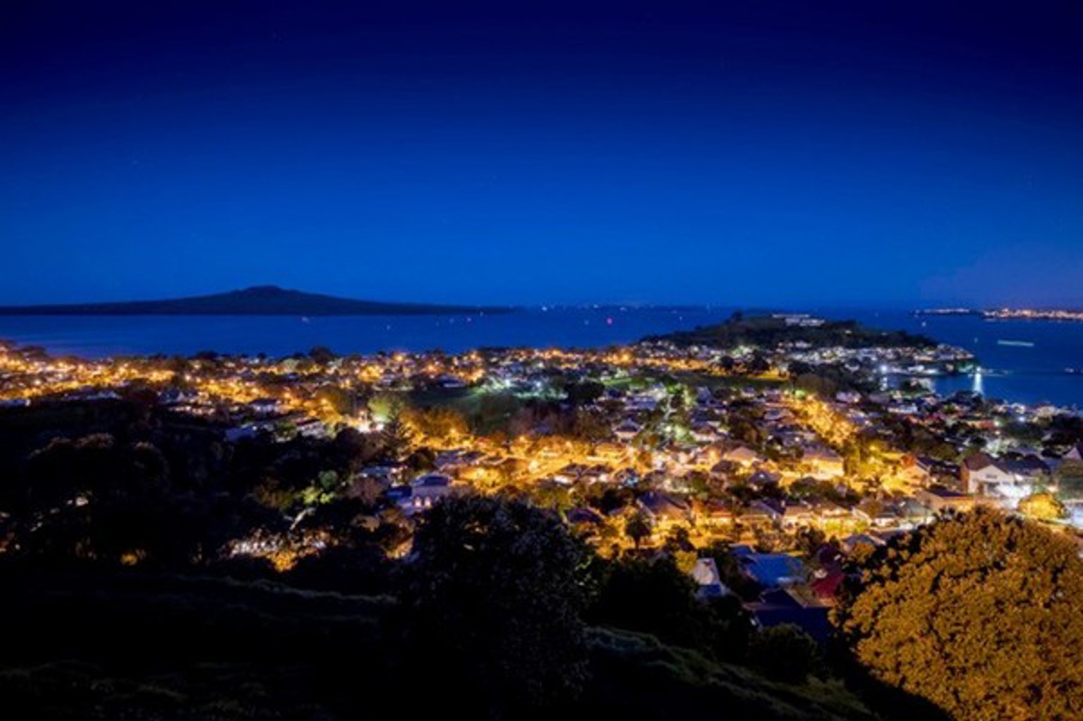 A photo of the lower North Shore at night before the streetlight upgrade. There is an orange glow from the streetlights.