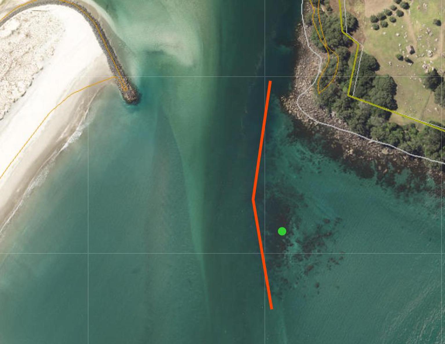 Aerial view of a coastal area with a breakwater, rocky shoreline, and an orange line marking a boundary.