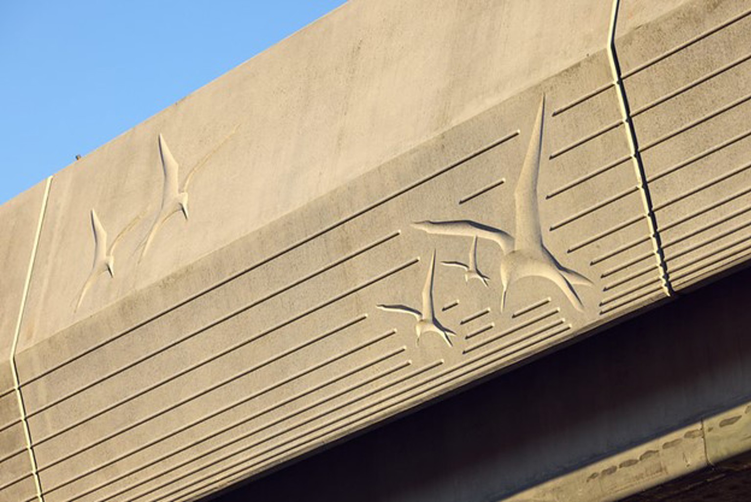 A close-up detail of the bird images engraved into the exterior wall of the flyover.