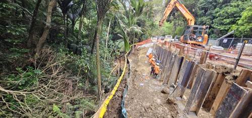 Digger and workmen building retaining wall