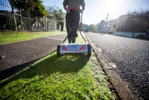 Person mowing berm in urban area.