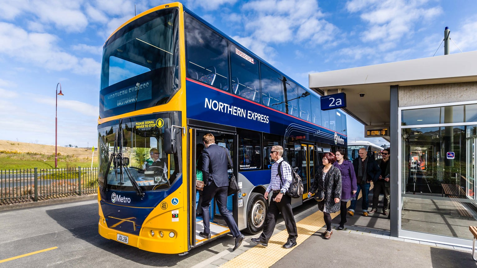 Image of several commuters boarding a yellow Northern Express double-decker bus.